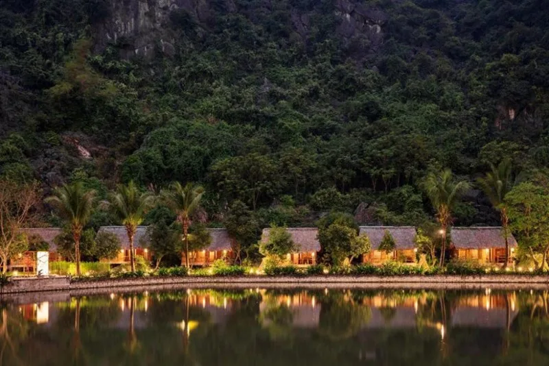 Dãy bungalow mái lá lên đèn bên mặt hồ dưới chân núi tại An's Eco Garden Resort