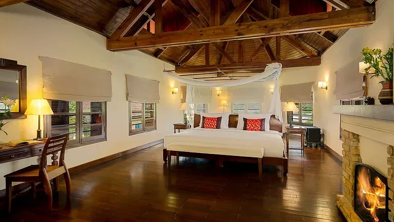 Phòng Villa Suite tại Ana Mandara Villas Dalat với trần gỗ, giường buông màn và lò sưởi đang cháy