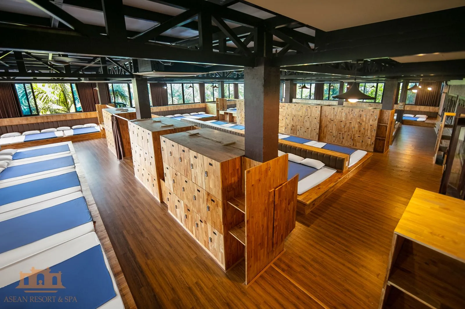 Phòng Cộng Đồng tại Asean Resort & Spa: sàn gỗ, đệm xanh trắng xếp liền, dãy tủ khóa gỗ ở giữa