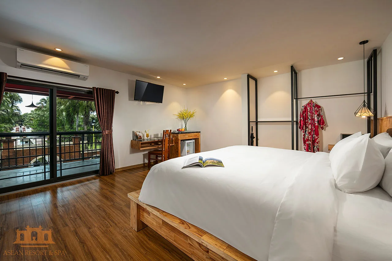 Phòng Superior của Asean Resort & Spa với giường gỗ lớn, sàn gỗ và ban công cửa kính nhìn ra hàng cọ