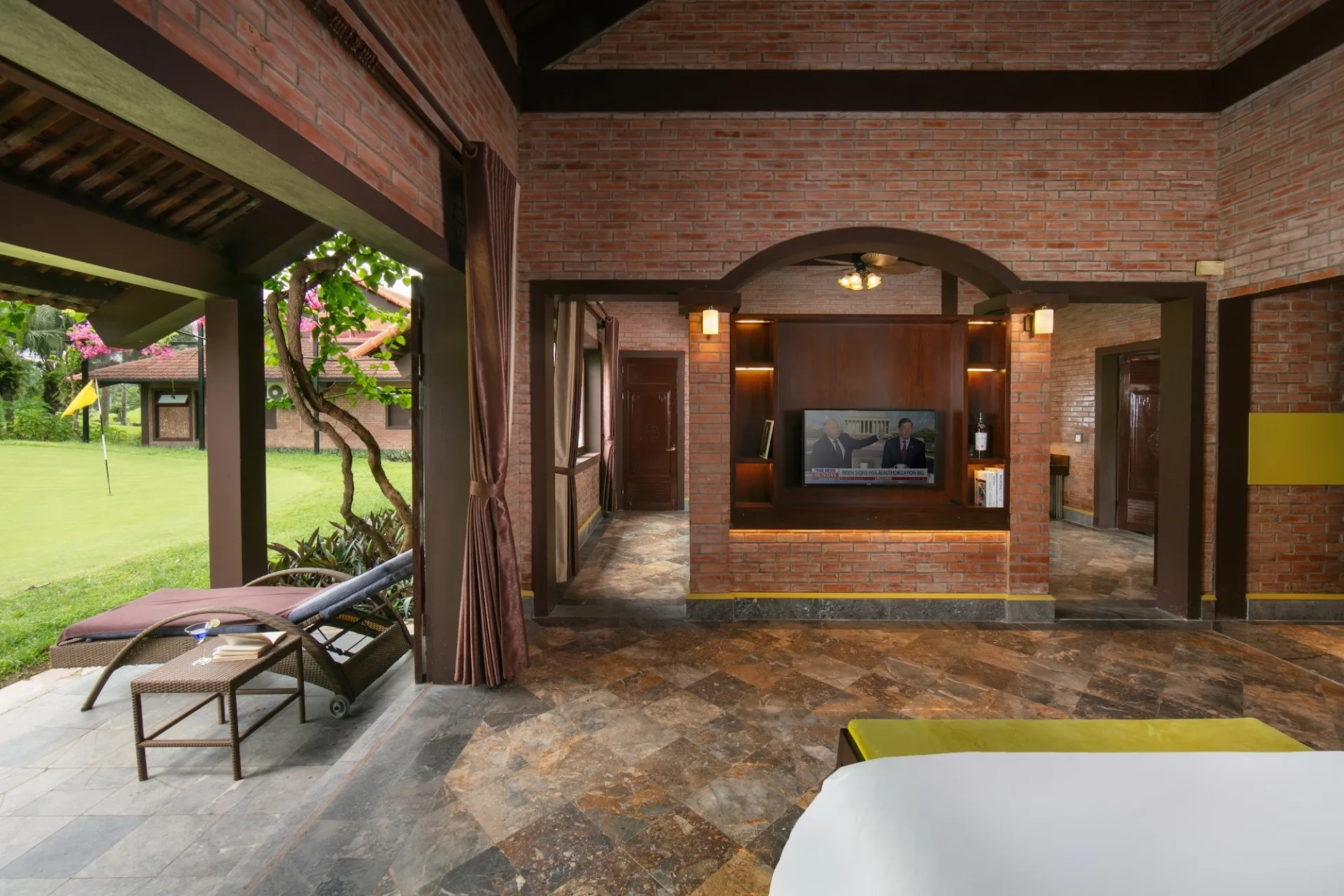 Phòng khách Grand Suite Bungalow tại Asean Resort mở cửa ra hiên có ghế nằm, nhìn ra lỗ golf cắm cờ vàng