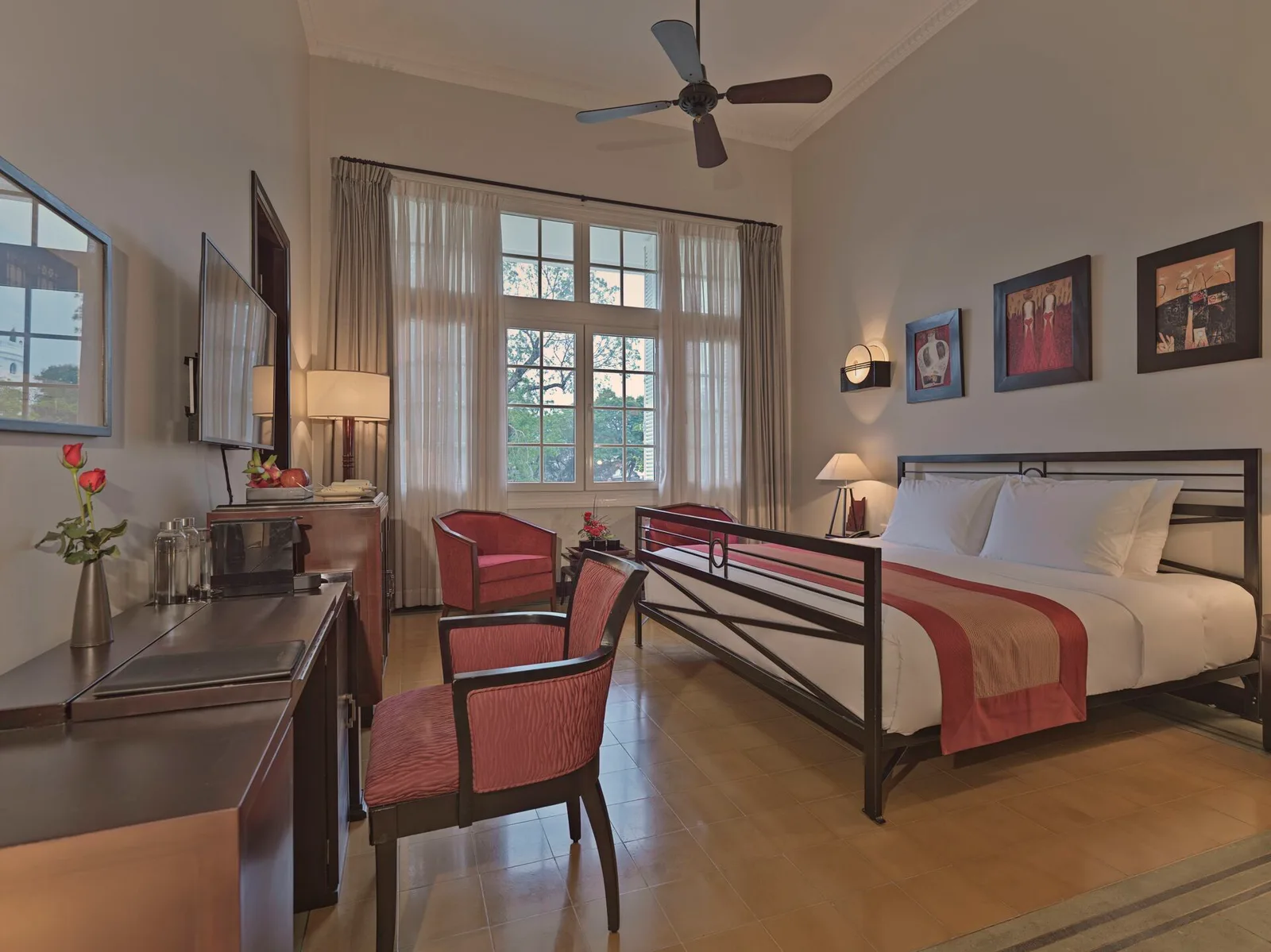 Phòng Deluxe Colonial tại Azerai La Résidence Huế với trần cao, quạt trần, sàn gạch men và cửa sổ lớn nhìn ra cây xanh