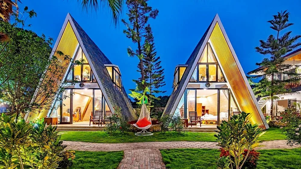 Hai căn villa mái A-frame lên đèn giữa bãi cỏ và lối đi gạch tại Bái Đính Garden Resort & Spa