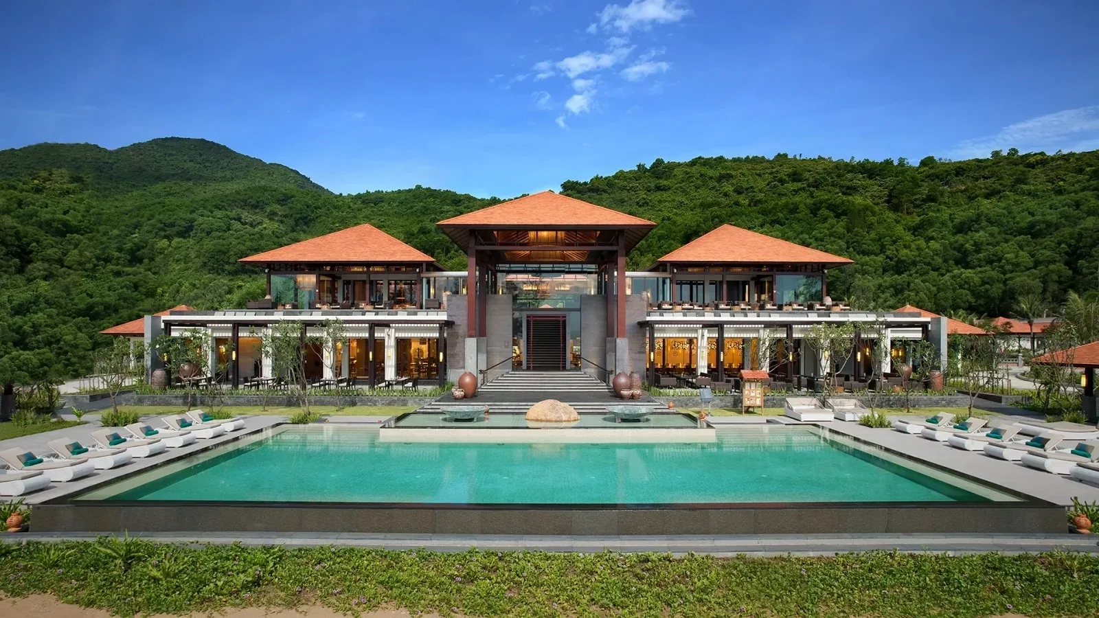Nhà đón khách mái ngói cam và hồ bơi vô cực trung tâm của Banyan Tree Lăng Cô dưới chân đồi xanh