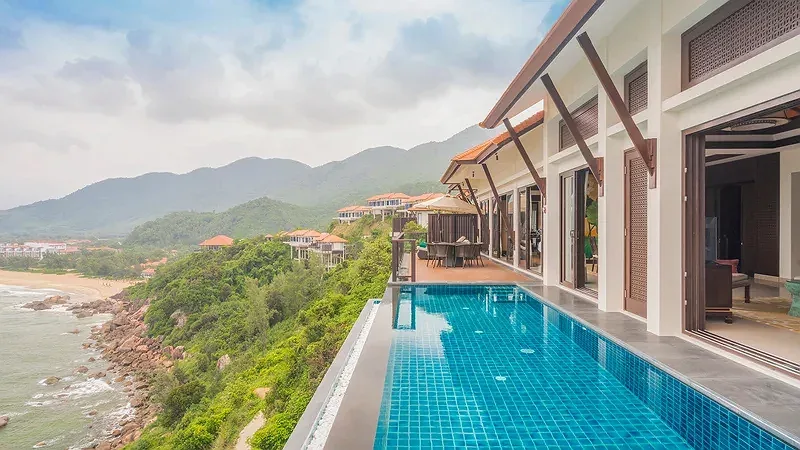 Two-Bedroom Seaview Hill Pool Villa ở Banyan Tree Lăng Cô, hồ bơi vô cực lát gạch xanh trên triền đồi nhìn xuống biển và bãi đá