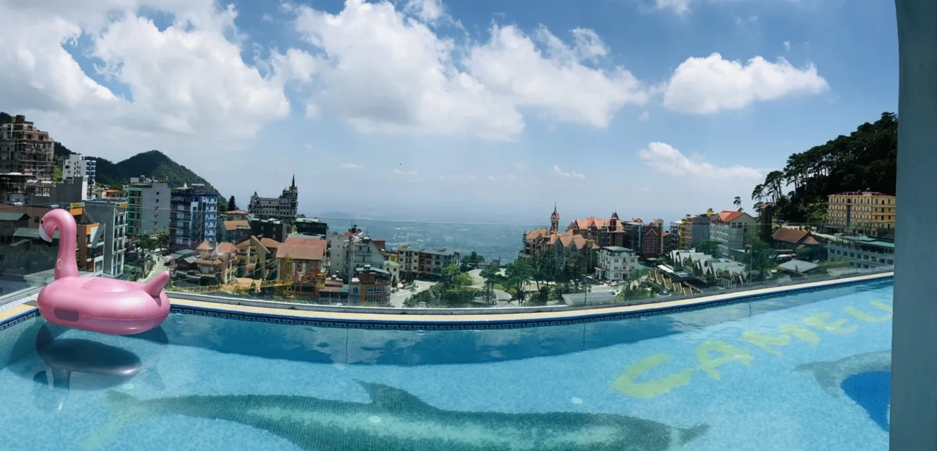 Bể bơi vô cực trên tầng thượng Camellia Luxury Hotel Tam Đảo, phao hồng trên mặt nước, phía dưới là mái nhà thị trấn và đồi núi