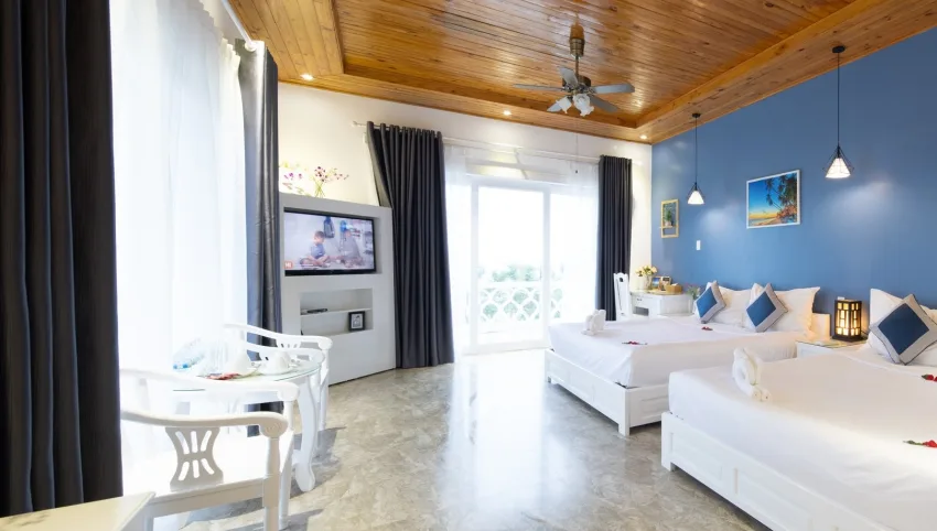 Phòng Family – Hướng biển của Casa Maya Resort Vĩnh Hy với hai giường lớn, trần gỗ, tường xanh và cửa kính mở ra ban công