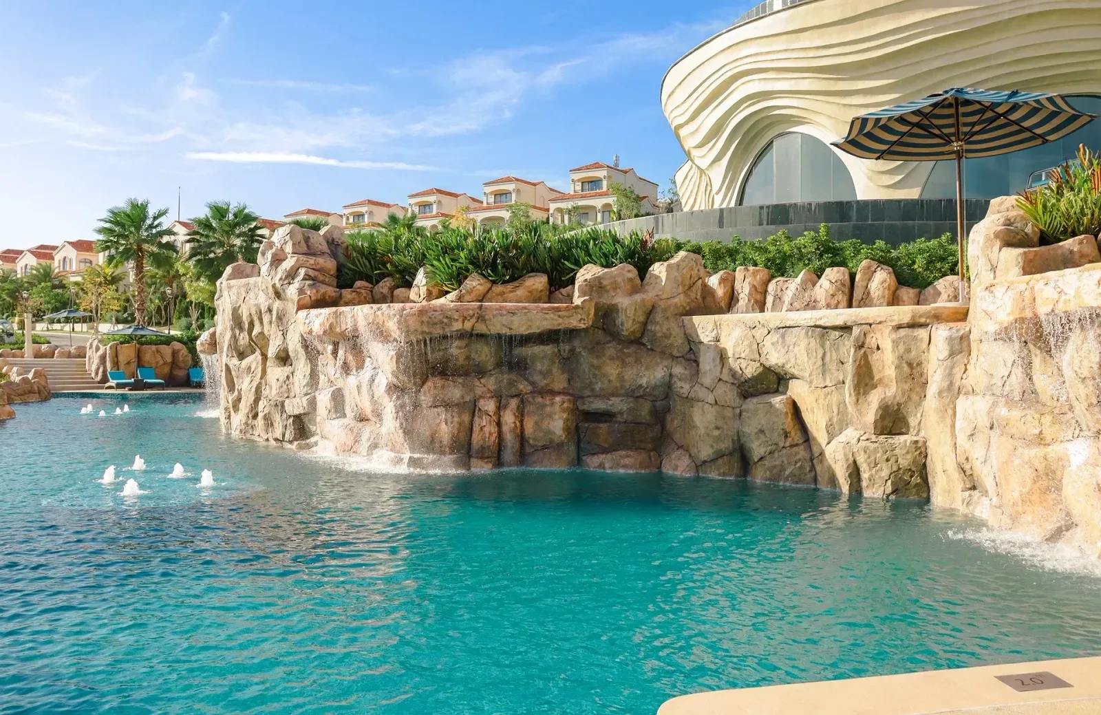 Hồ bơi có thác nước đá của Centara Mirage Resort Mui Ne, phía sau là villa mái ngói đỏ