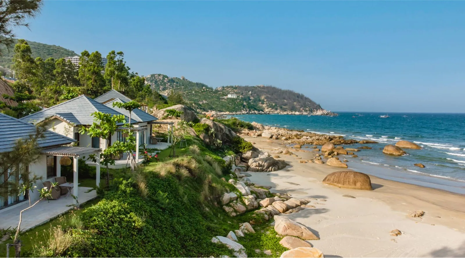 Dãy bungalow của Crown Retreat Quy Nhơn trên sườn đồi, nhìn xuống bãi cát và ghềnh đá