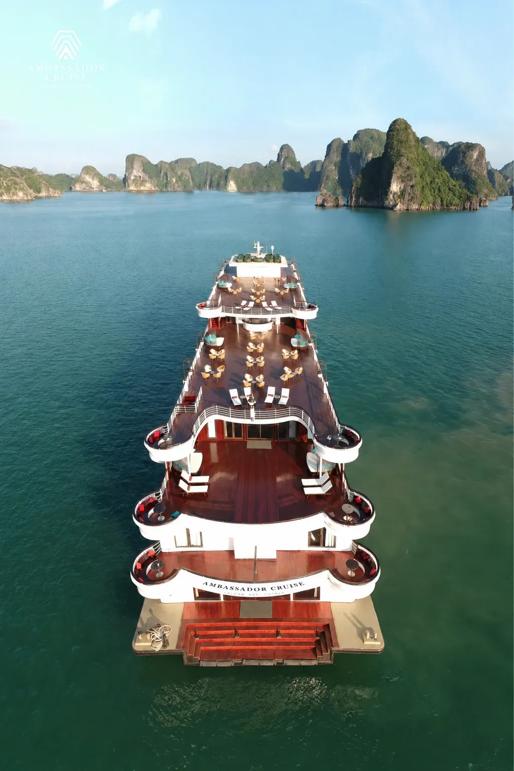 Các tầng sundeck lát gỗ của du thuyền Ambassador Hạ Long nhìn từ trên cao, núi đá vịnh phía trước