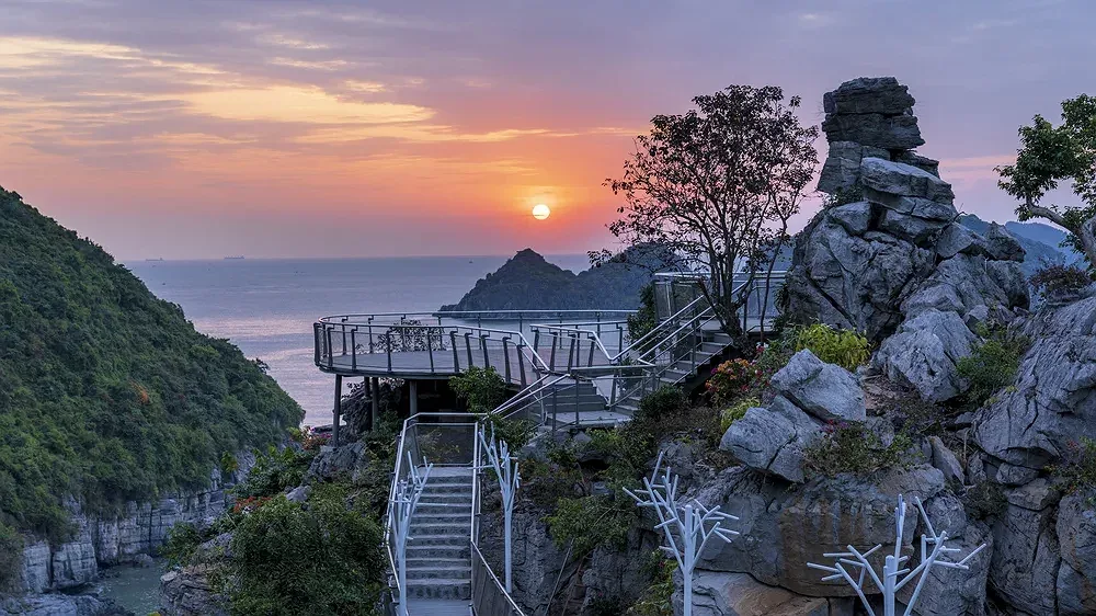 Cầu kính Skywalk của Flamingo Cat Ba Resort - Forest Tower men theo vách đá, phía xa mặt trời lặn trên biển