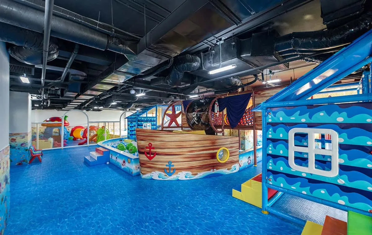 Khu Flamingo Kids Club trong nhà ở Flamingo Đại Lải với sàn xanh họa tiết sóng nước, mô hình thuyền cướp biển, nhà bóng và cầu trượt