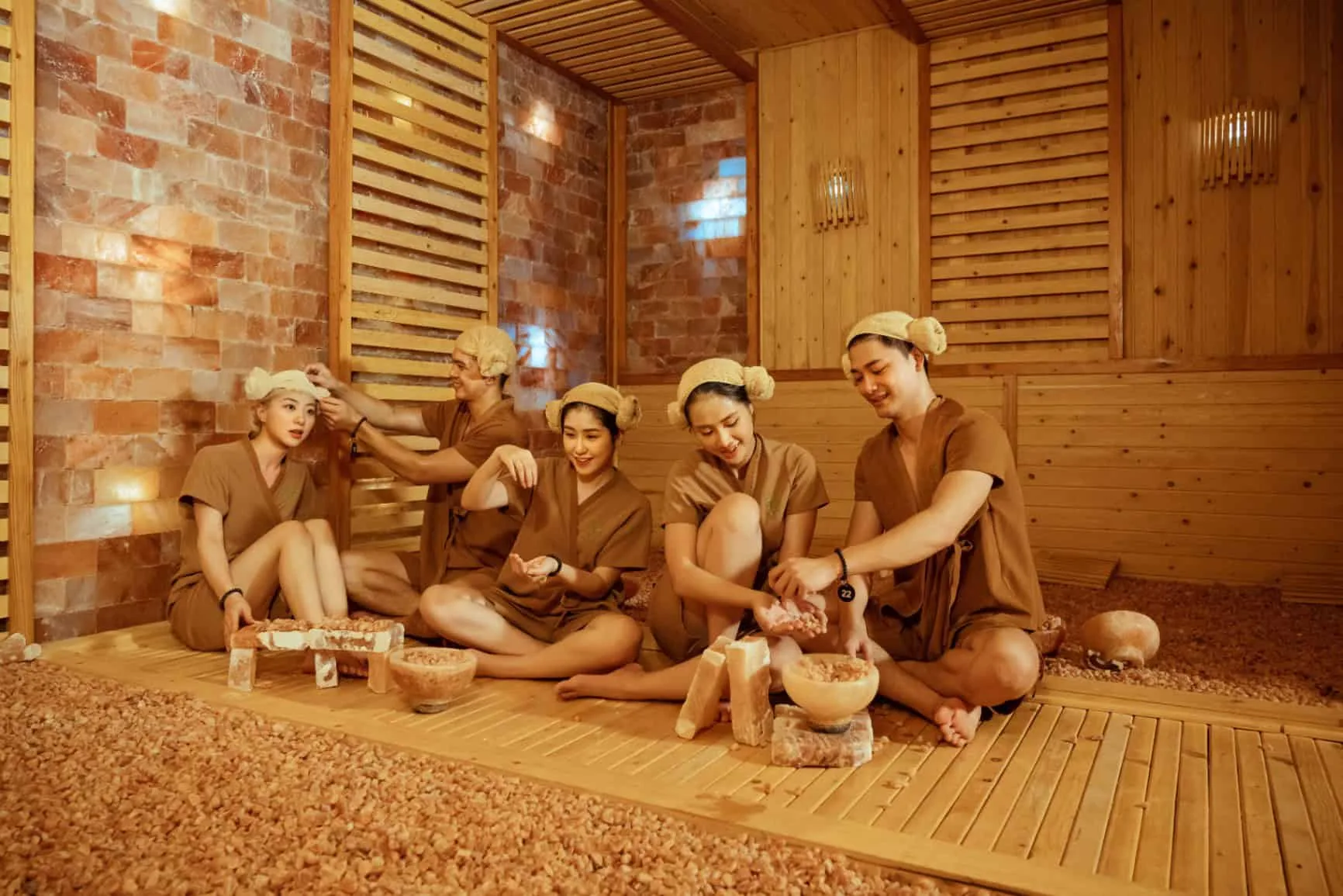 Phòng xông muối Himalaya của SEVA Onsen & Spa, tường gạch muối phát sáng, khách mặc đồ xông ngồi trên sàn gỗ tại Flamingo Đại Lải Resort
