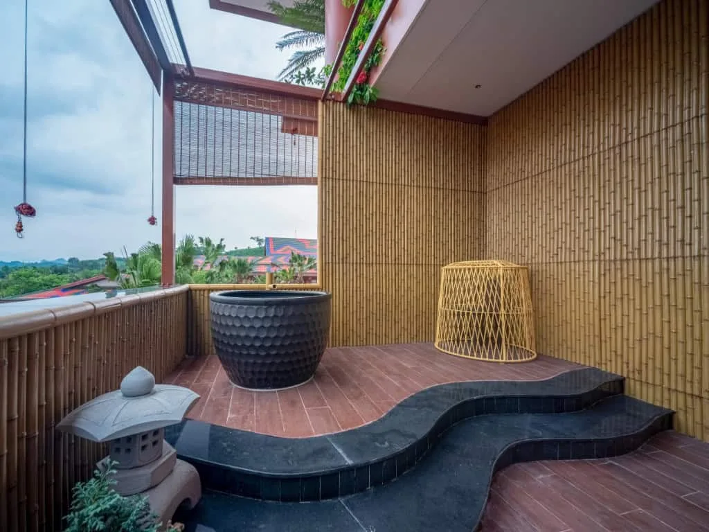 Ban công vách tre của Premier Residence với bồn ngâm gốm đen, bậc đá uốn lượn và đèn đá kiểu Nhật tại Flamingo Tân Trào
