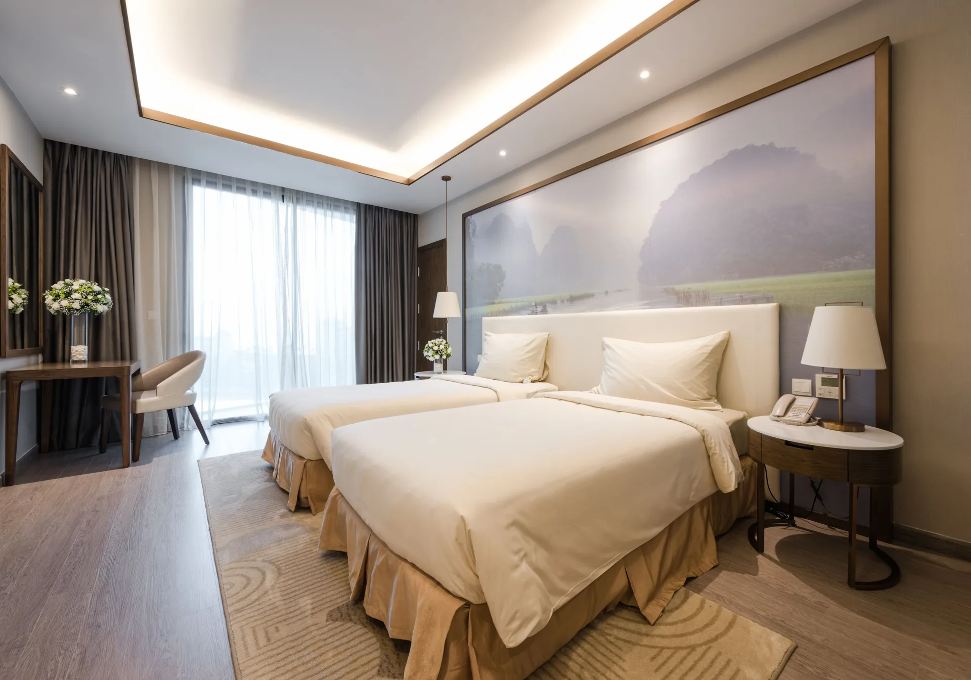 Phòng Grand Comfort Twin với hai giường đơn kê cạnh nhau, tranh tường núi đá vôi phía sau và cửa kính rèm voan