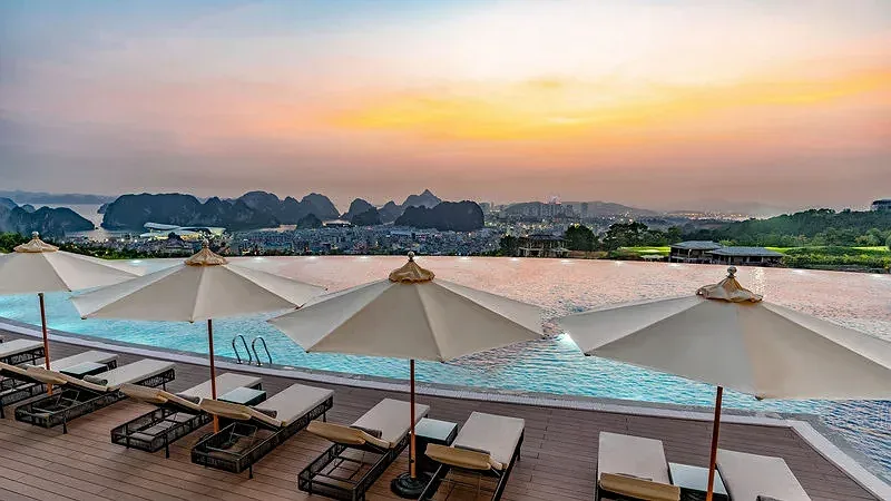 Bể bơi vô cực trên đồi của FLC Halong Bay Golf Club & Luxury Resort với hàng ô trắng, phía xa là thành phố và núi đá vịnh Hạ Long