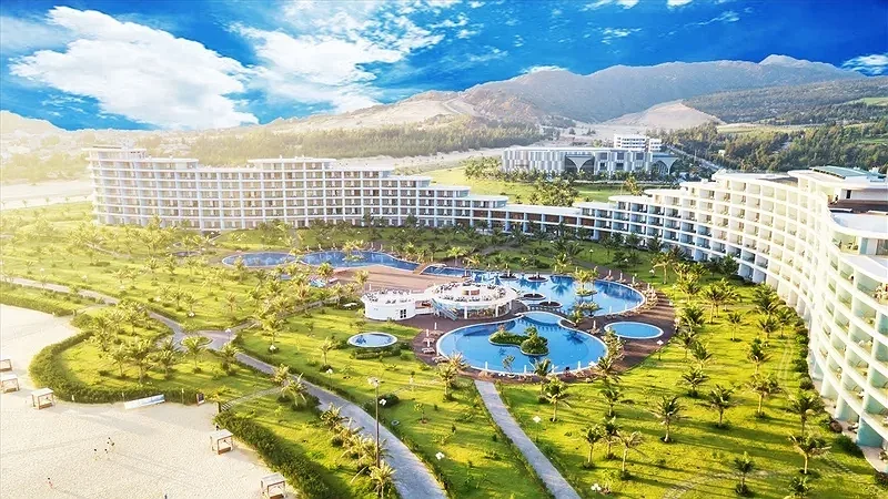 Toàn cảnh FLC Luxury Hotel Quy Nhơn với dãy nhà trắng ôm cụm bể bơi, hàng dừa và bãi cát