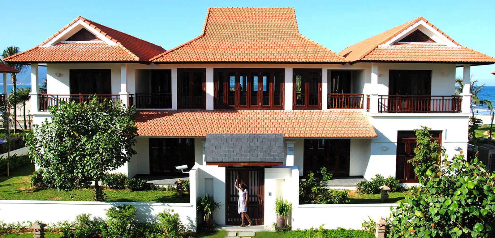 Biệt thự hai tầng mái ngói đỏ của Furama Villas Danang với ban công gỗ, cổng riêng và biển phía sau