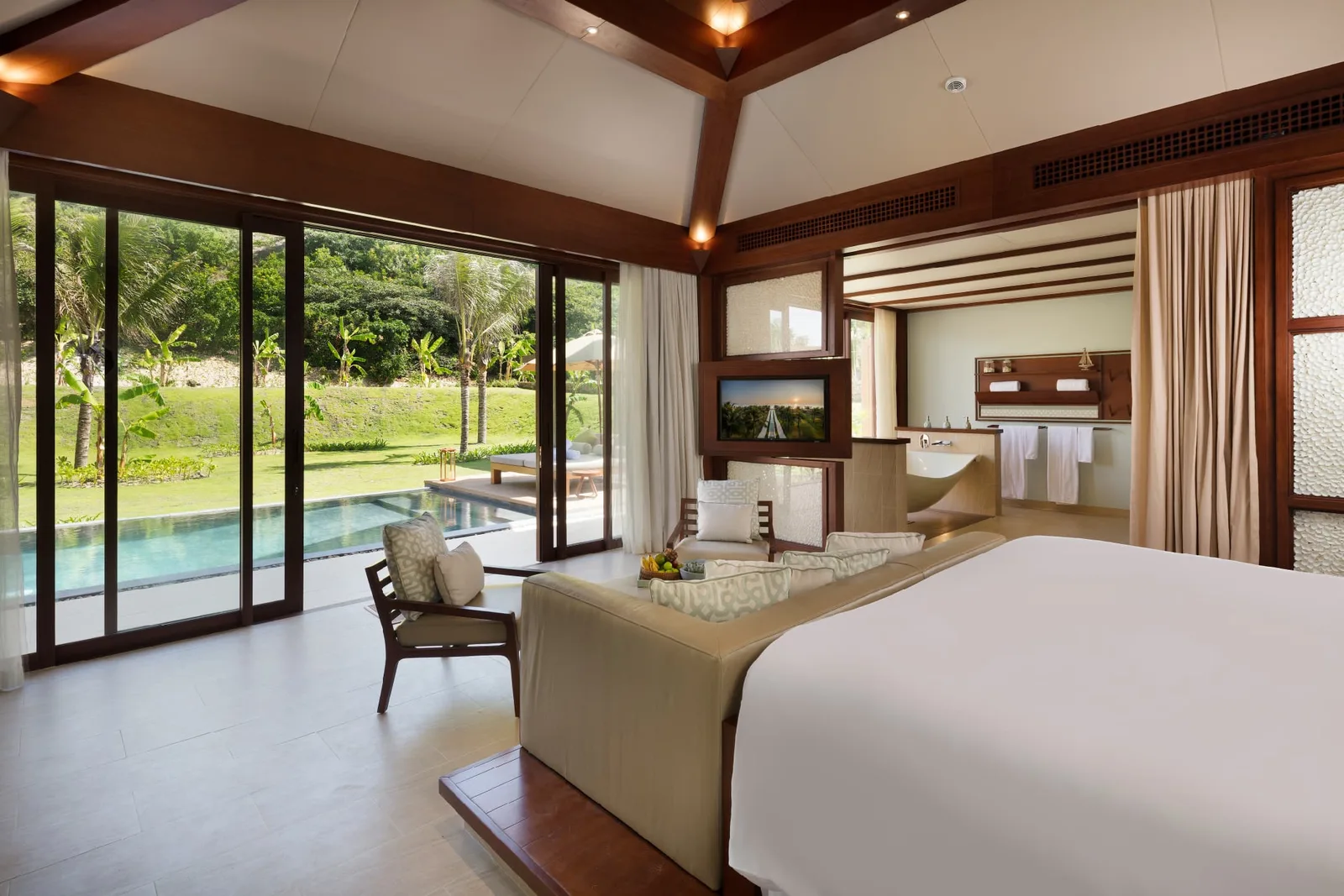 Phòng ngủ Hideaway Pool Villa tại Fusion Resort Cam Ranh, cửa kính mở ra hồ bơi riêng và bãi cỏ xanh