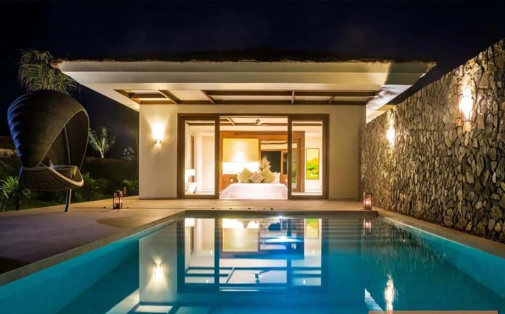 Villa hồ bơi riêng của Fusion Resort Phu Quoc lúc tối, phòng ngủ mở thẳng ra hồ bơi, tường đá và ghế treo