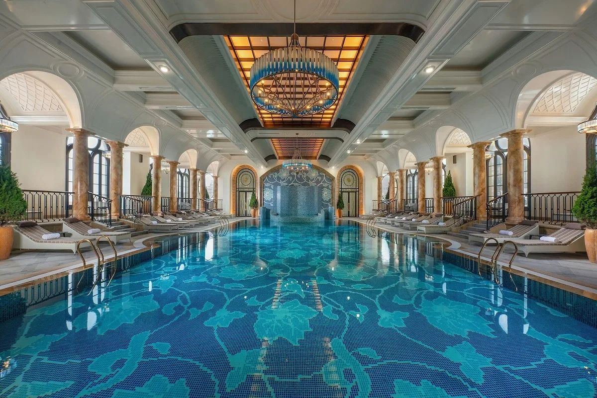 Bể bơi bốn mùa trong nhà của Hôtel de l'Amour Tam Đảo lát mosaic xanh, hai bên là hàng cột và vòm cửa cổ điển