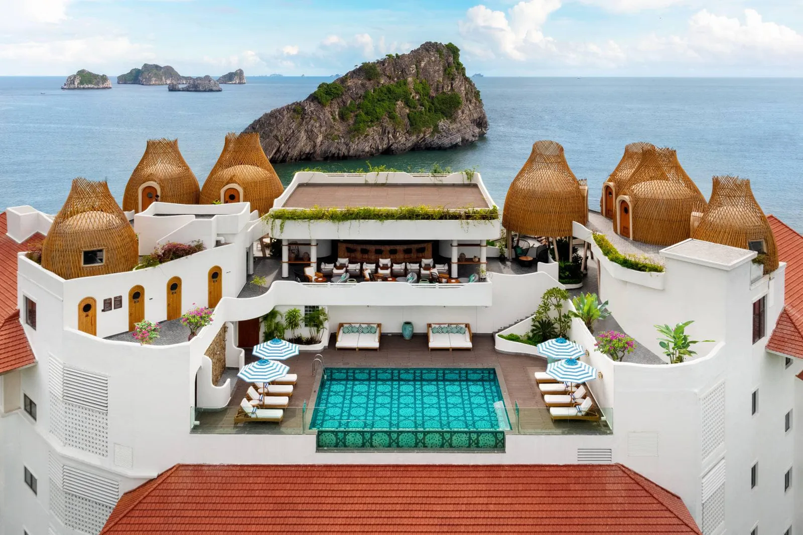 Sân thượng Hotel Perle d’Orient Cat Ba MGallery với hồ bơi xanh ngọc, các mái vòm đan tre, phía sau là núi đá giữa vịnh