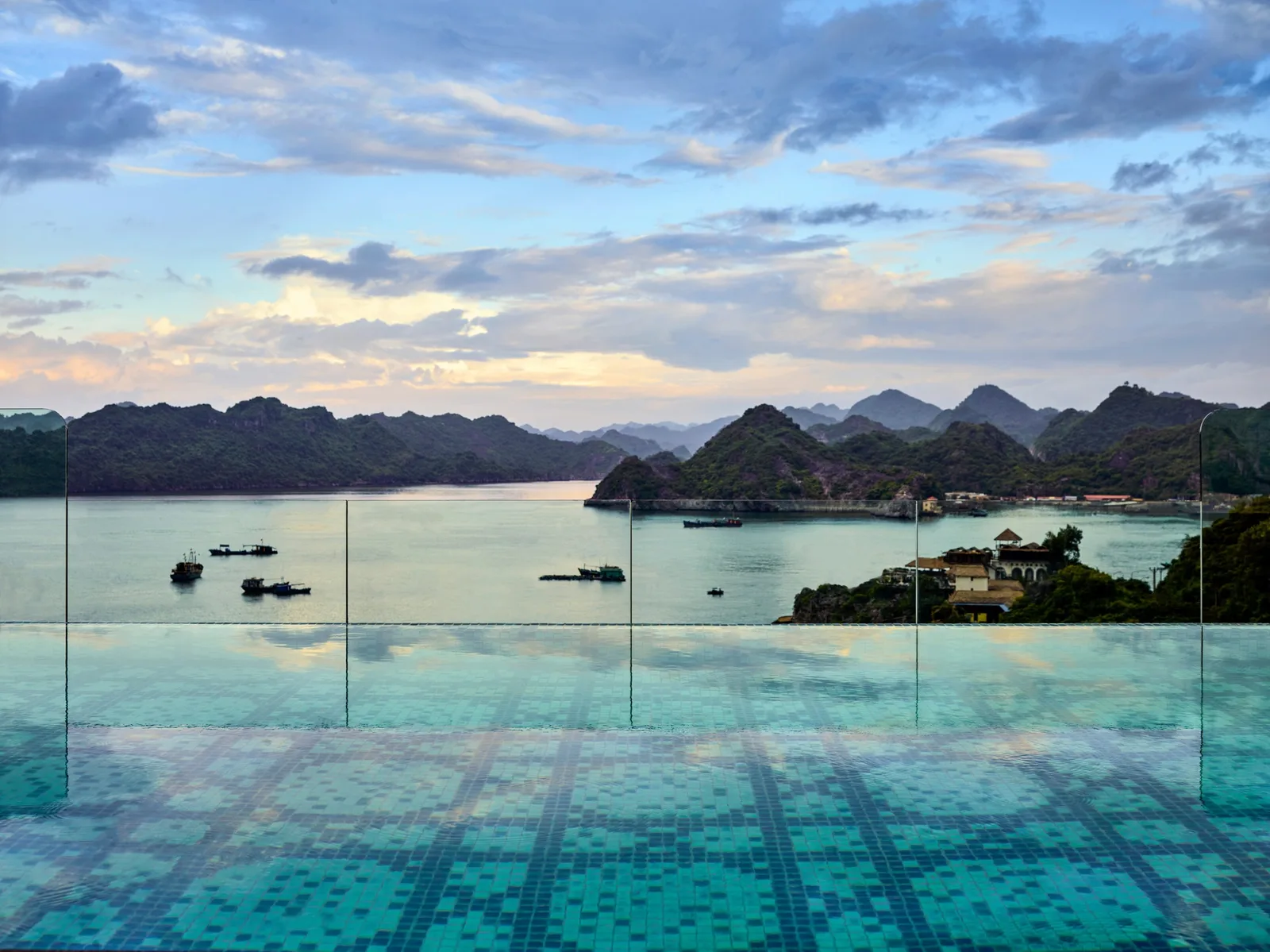 Bể bơi vô cực trên tầng thượng Hôtel Perle d'Orient Cát Bà - MGallery nhìn ra mặt vịnh, thuyền neo và dãy núi đá lúc chiều