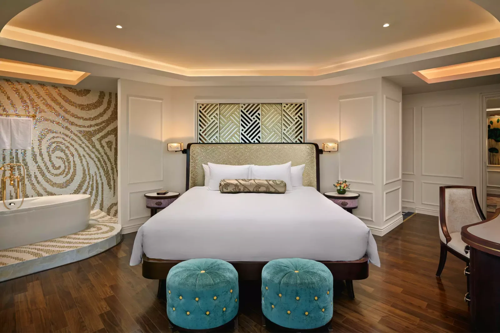 Phòng Deluxe Suite tại Hotel Royal Hoi An - MGallery, bồn tắm trắng đặt trên bục lát mosaic xoáy vàng cạnh giường King