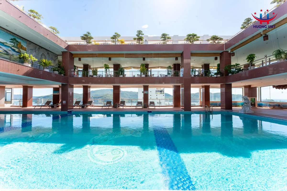 Hồ bơi trên tầng cao của Hương Việt Hotel Quy Nhơn, hai tầng hành lang cây cảnh và núi phía xa
