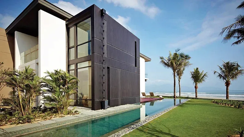 Ocean Villa tại Hyatt Regency Danang với hồ bơi dài chạy ra phía biển, bãi cỏ và hàng dừa