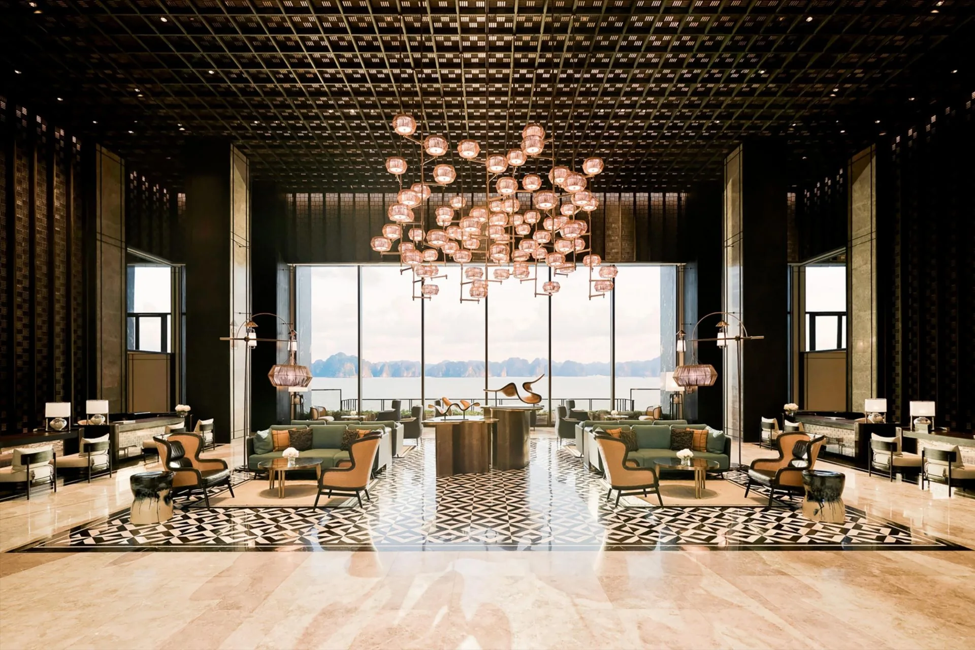Sảnh đón InterContinental Halong Bay Resort trần lưới cao, chùm đèn lồng đồng, cửa kính lớn nhìn ra vịnh và núi đá