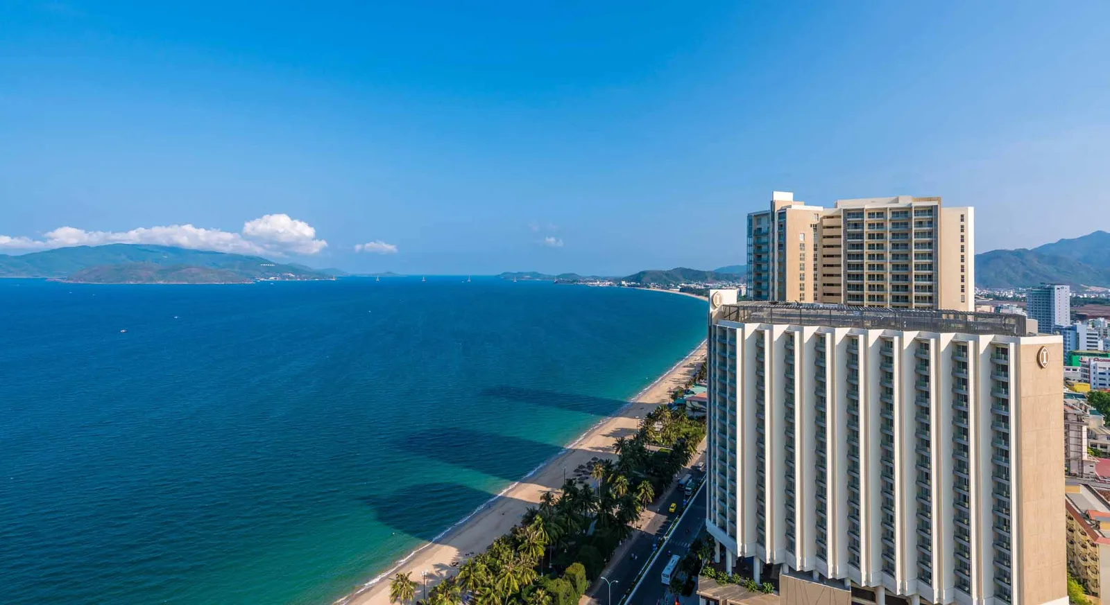 Tòa khách sạn InterContinental Nha Trang nhìn từ trên cao, bên cạnh bãi cát Trần Phú, hàng dừa và mặt vịnh xanh