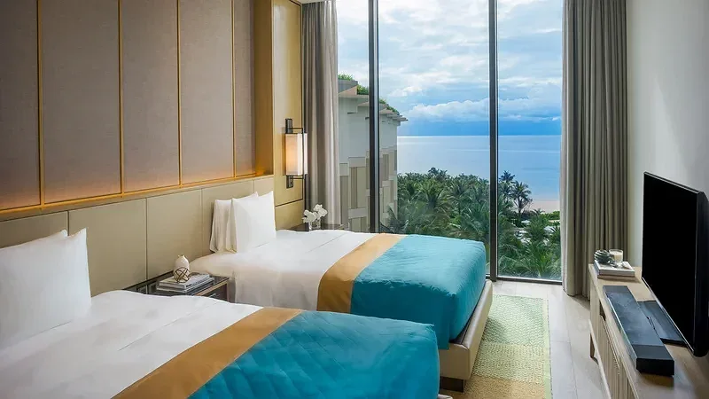 Phòng hai giường đơn tại InterContinental Phu Quoc Long Beach Resort, cửa kính lớn nhìn xuống hàng dừa và biển