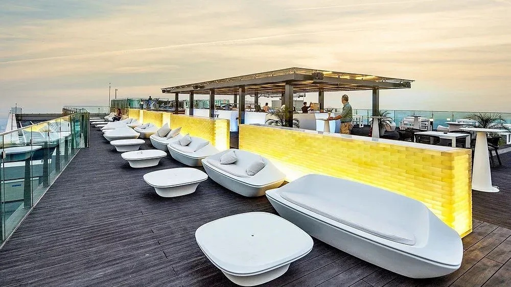 Sky lounge Top of Hanoi trên nóc Lotte Hotel Hanoi với sofa trắng dọc lan can kính và quầy bar ốp đèn vàng lúc chiều muộn