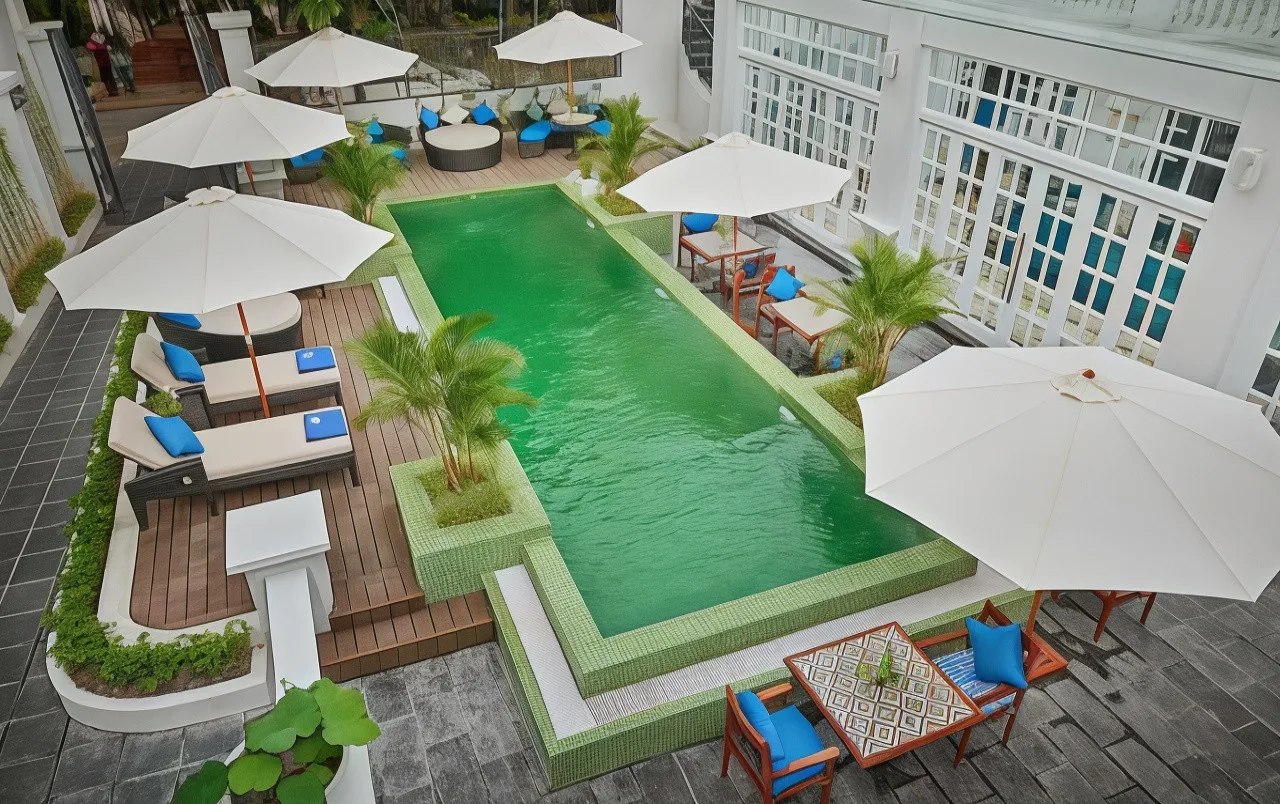 Bể bơi mosaic xanh giữa sân hiên có dù trắng và ghế tắm nắng ở Manoir des Arts Hotel
