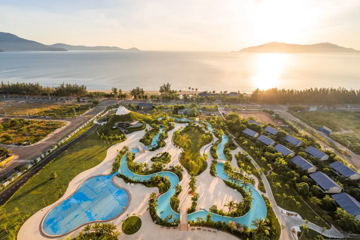 Ảnh flycam công viên nước ngoài trời của Mikazuki Japanese Resorts & Spa với hồ bơi uốn lượn, phía sau là biển lúc hoàng hôn