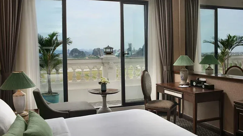 Phòng khách sạn có cửa kính lớn mở ra ban công, xa xa là dãy núi đá vôi tại Ninh Binh Hidden Charm Hotel & Resort