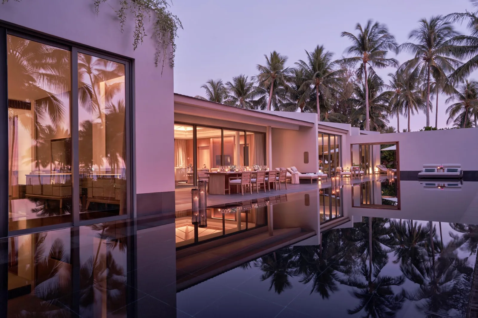 Beach Pool Villa tại Regent Phu Quoc lúc chạng vạng: hồ bơi riêng mặt gương phản chiếu hàng dừa, phòng ăn kính sáng đèn bên cạnh