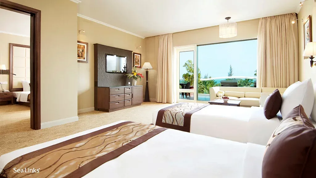 Phòng Family Suite của Sea Links City Resort Mui Ne với hai giường, cửa thông sang phòng ngủ thứ hai và cửa kính mở ra hiên nhìn biển