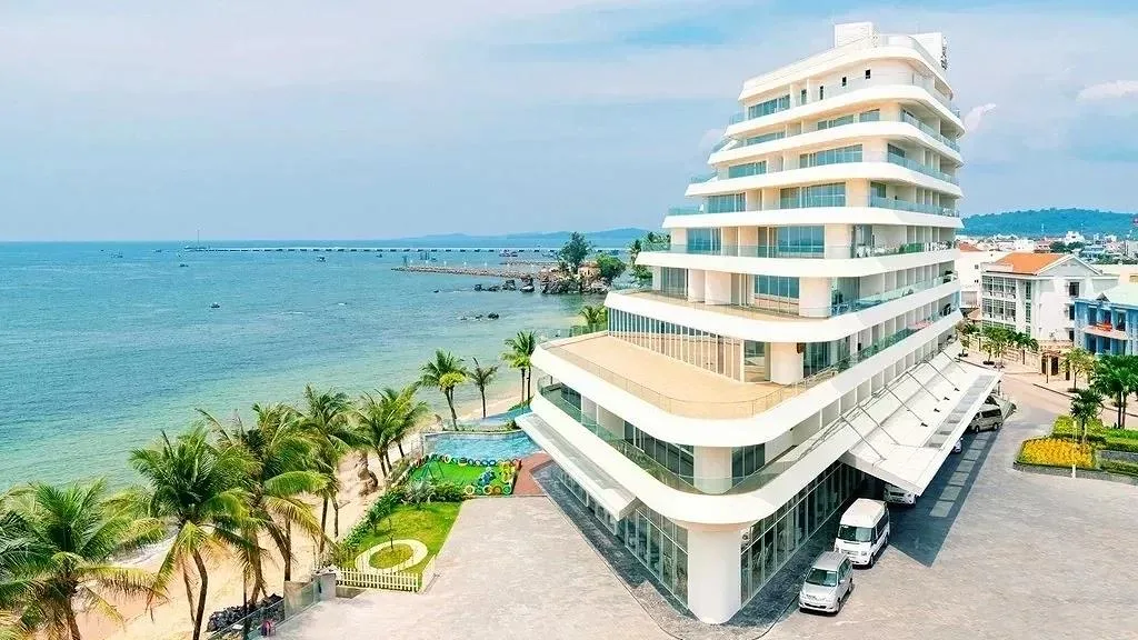 Tòa nhà trắng nhiều tầng của Seashells Phu Quoc Hotel & Spa bên bờ biển Dương Đông, có hồ bơi và sân chơi trẻ em phía trước