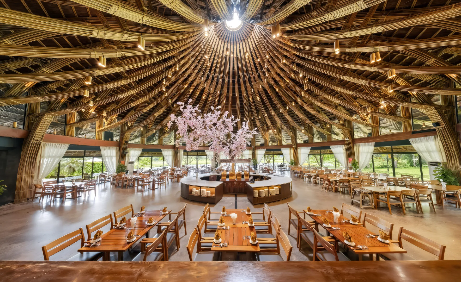 Bên trong Nhà hàng Nón với vòm tre đan tỏa tròn, quầy buffet tròn ở giữa và bàn gỗ bày sẵn, Serena Resort Kim Bôi