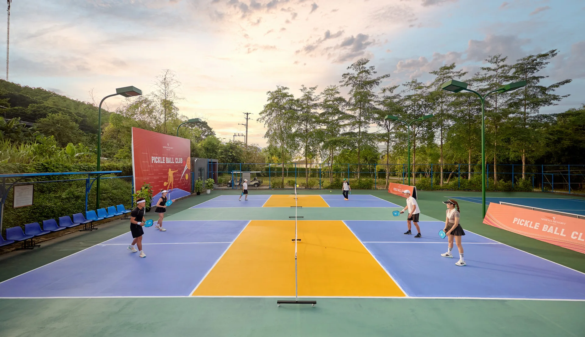 Sân pickleball ngoài trời của Serena Resort Kim Bôi lúc chiều, mặt sân xanh tím vàng, bảng Pickle Ball Club