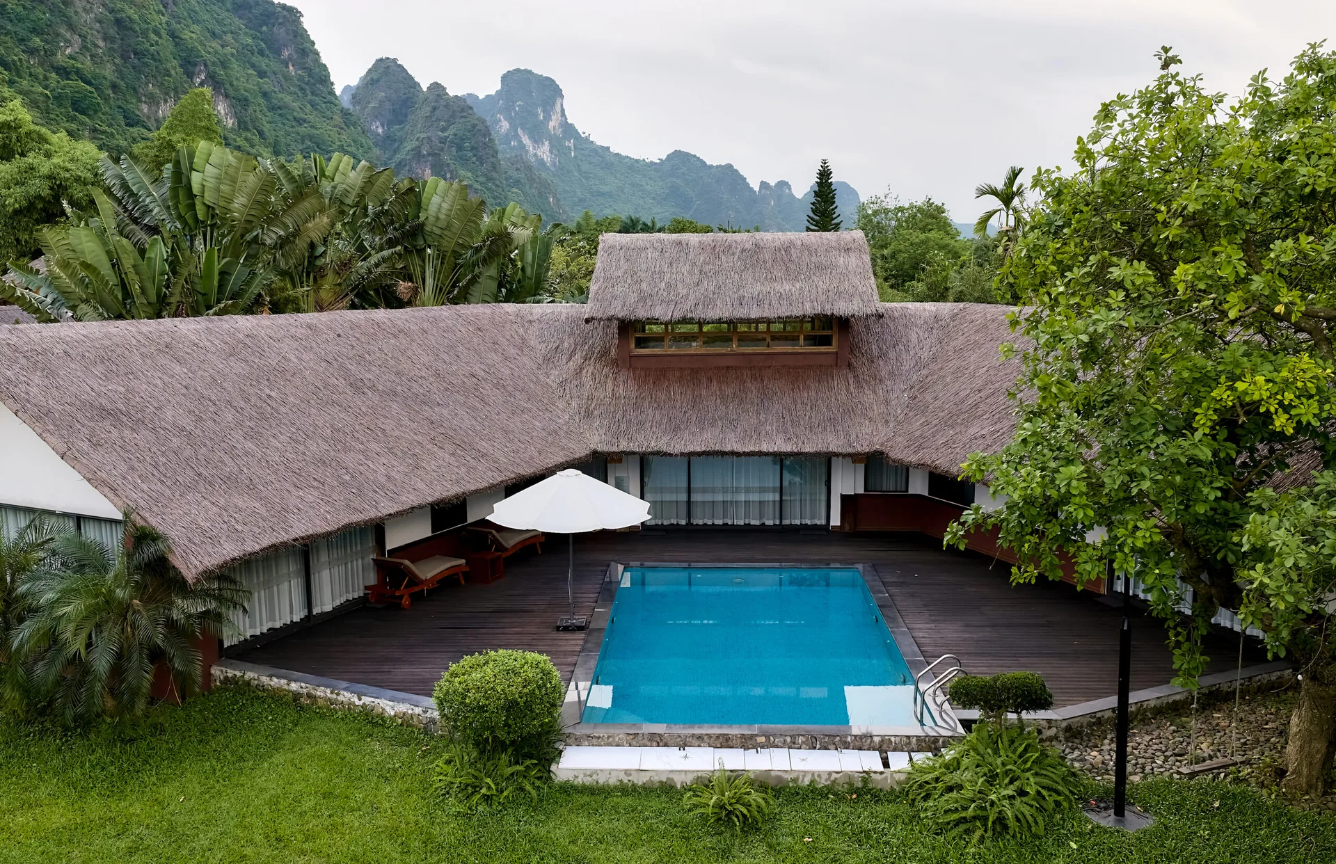 Onsen Villa mái tranh hình chữ U ôm bể bơi riêng, sàn gỗ có ghế tắm nắng, núi đá vôi phía sau tại Serena Resort Kim Bôi