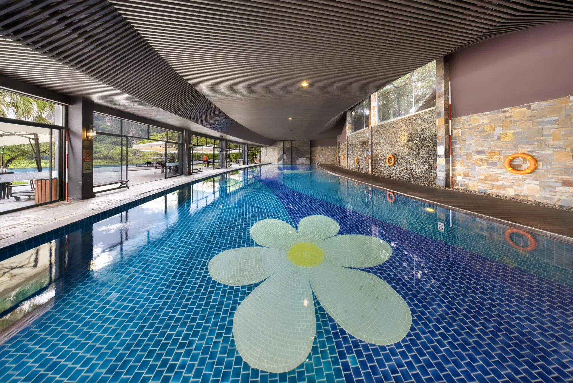 Bể khoáng nóng trong nhà tại Serena Resort Kim Bôi, đáy gạch xanh có hình bông hoa, trần nan gỗ uốn lượn