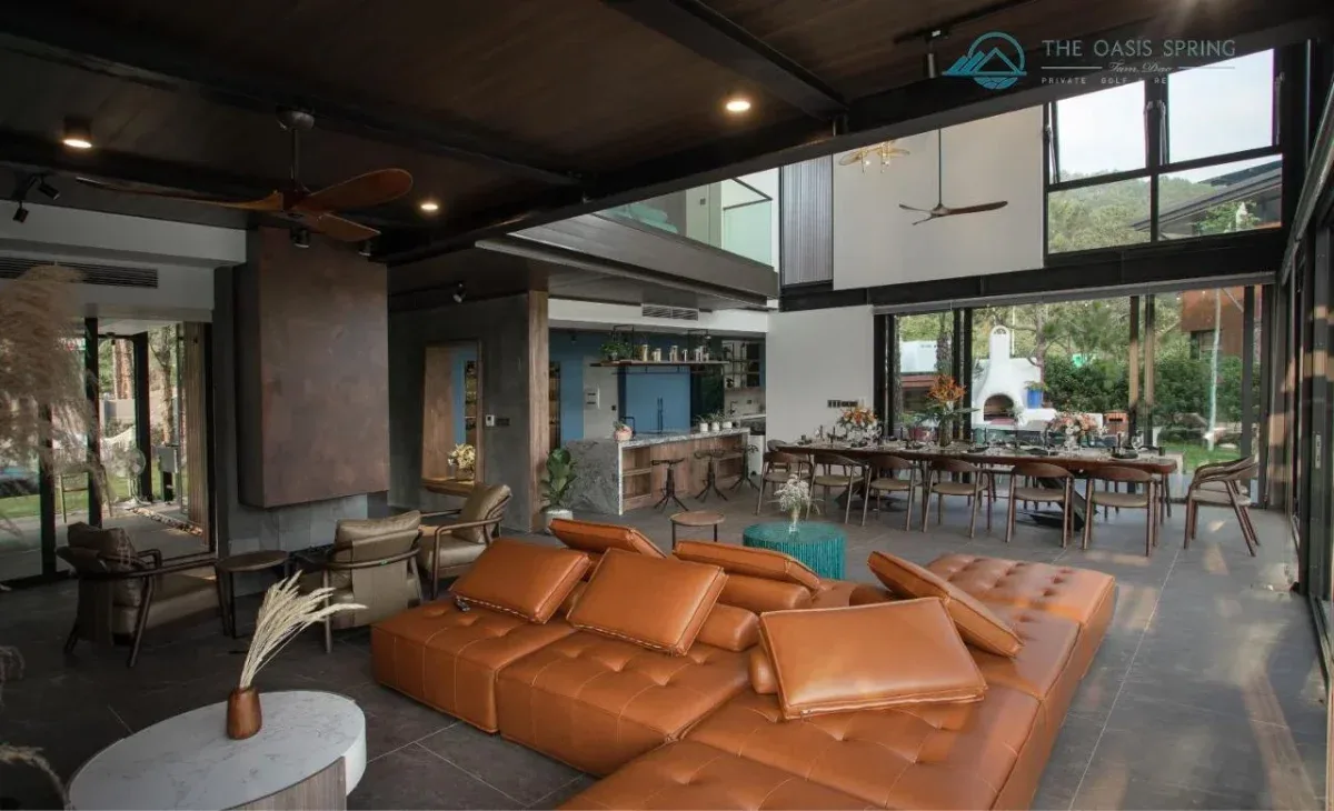 Phòng khách Family Suite Villa tại Tam Đảo Golf & Resort với sofa da lớn, bàn ăn dài cho cả nhóm và quầy bếp phía sau
