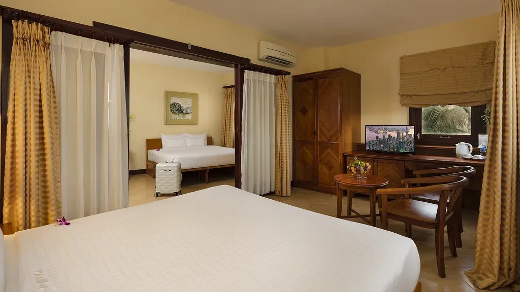 Family Room tại Terracotta Resort & Spa với hai khu ngủ liên thông ngăn bằng rèm, mỗi khu một giường lớn, tủ gỗ và bàn uống nước