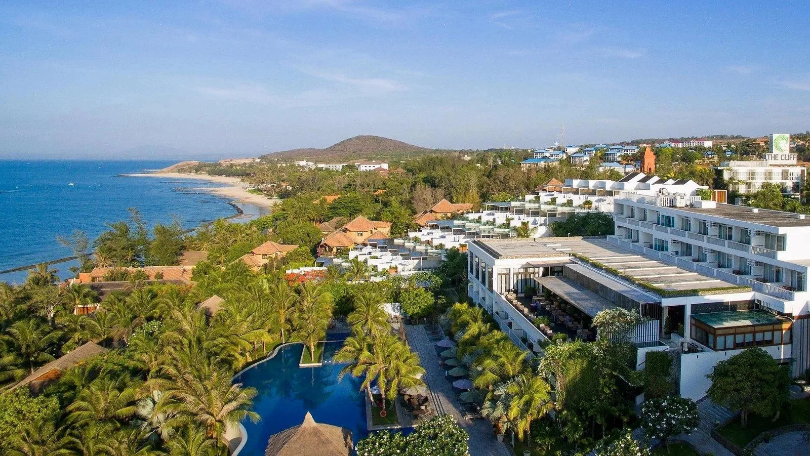 Toàn cảnh The Cliff Resort & Residences nhìn từ trên cao: khối nhà trắng, hồ bơi giữa vườn dừa và dải bờ biển Phan Thiết