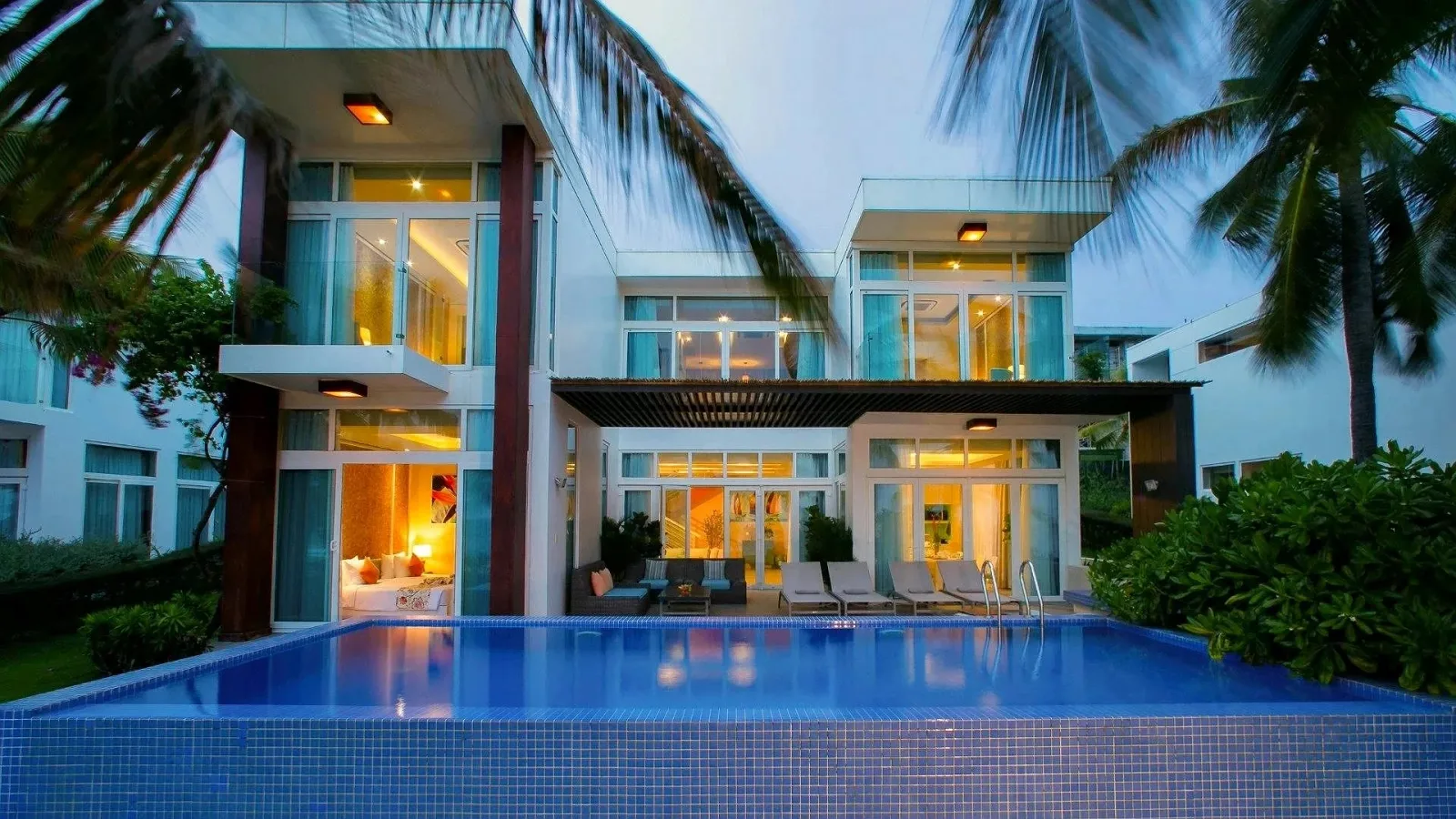Villa hai tầng tường kính của The Cliff Resort & Residences với hồ bơi riêng lát gạch xanh và ghế tắm nắng phía trước