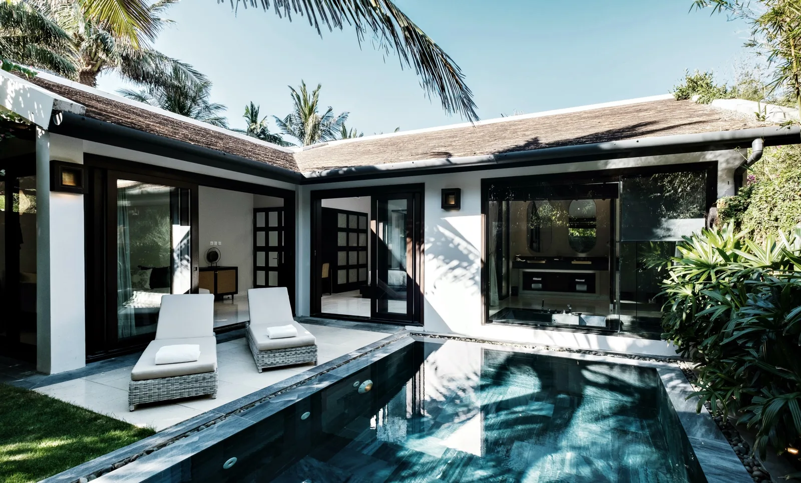 Biệt thự 1 phòng ngủ tại TIA Wellness Resort Đà Nẵng với hồ bơi riêng lát đá xanh, hai ghế tắm nắng và cửa kính mở vào phòng ngủ