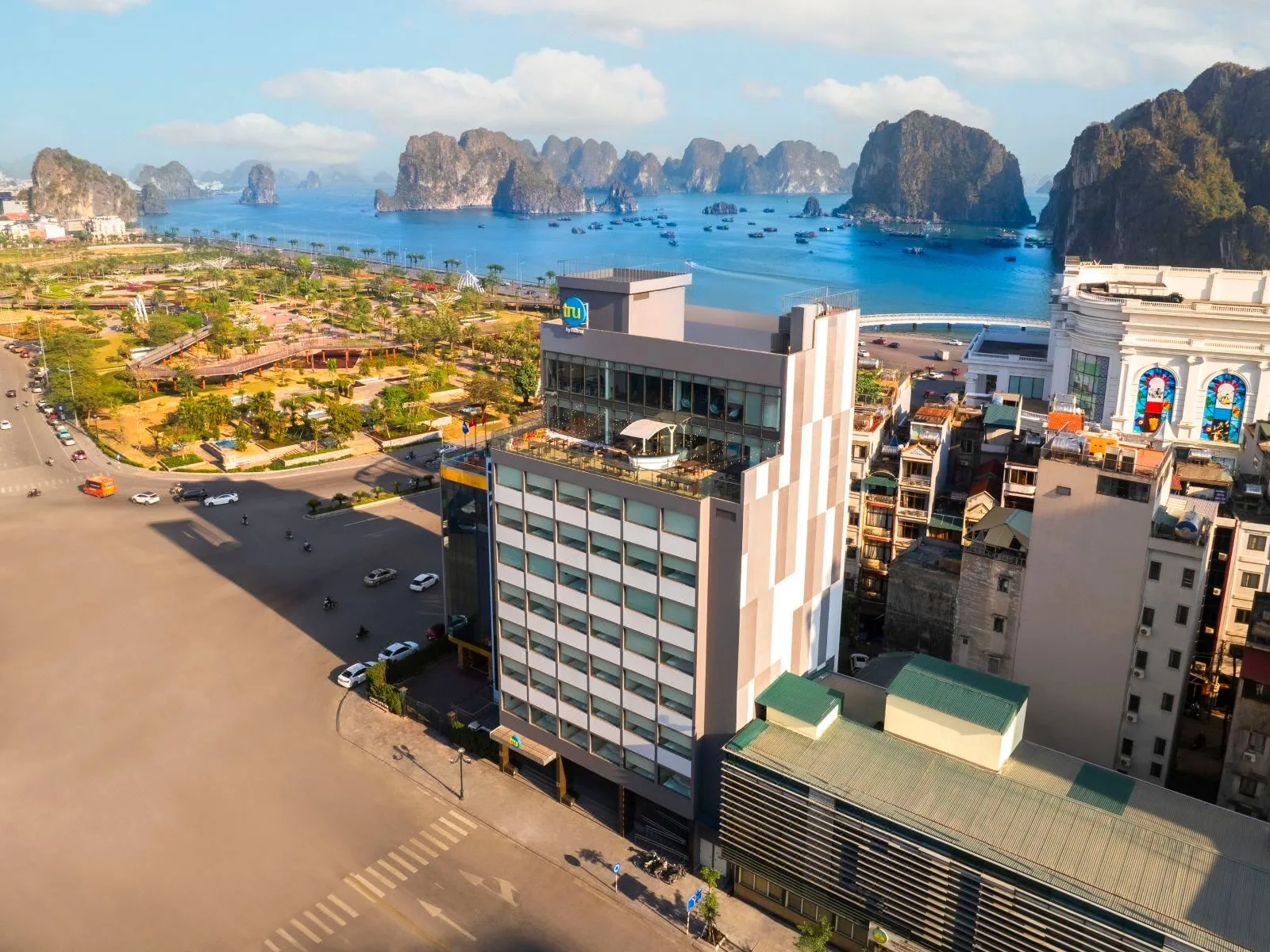 Tòa khách sạn Tru by Hilton Ha Long Hon Gai Centre giữa khu phố Hòn Gai, phía sau là vịnh với các đảo đá